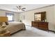 This bedroom features a ceiling fan, patterned wallpaper, and a wood dresser with a mirror at 59 Sycamore Dr, Carmel, IN 46033