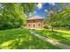 Charming brick two-story home with mature trees and a well-manicured lawn. The house has a walkway and multiple windows at 6125 N Olney St, Indianapolis, IN 46220
