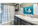 Bathroom with double sinks, an ocean themed accent wall, and bathtub with shower at 6315 Emerald Field Way, Indianapolis, IN 46221