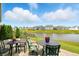 View of patio furniture overlooking beautiful pond with lush greenery and houses in the distance at 6315 Emerald Field Way, Indianapolis, IN 46221