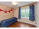 Rustic bedroom featuring wood-paneled accent wall, hardwood floors, and bright natural light at 6683 Manchester Dr, Fishers, IN 46038