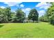 Large, expansive grassy backyard with mature trees and a couple of storage sheds at 6949 Crittenden Ave, Indianapolis, IN 46220