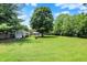 Expansive backyard with lush green lawn, mature trees, and storage shed, perfect for outdoor activities at 6949 Crittenden Ave, Indianapolis, IN 46220