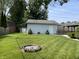 Backyard featuring a well-manicured lawn, mature landscaping, and a fire pit at 737 Howard St, Shelbyville, IN 46176