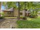 A serene backyard with a brick home, wooden deck, lush greenery, and decorative rock garden at 7612 Freedom Woods Dr, Indianapolis, IN 46259