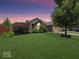 Charming brick home with a well-manicured lawn and mature landscaping at sunset at 8144 Grassy Meadow Cir, Indianapolis, IN 46259