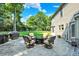 Exterior view featuring stone patio with outdoor seating, grill, and lush backyard at 8261 Twin Pointe Cir, Indianapolis, IN 46236