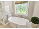 Bright bathroom showcasing a soaking tub, glass shower, and decorative window with a garden view at 8261 Twin Pointe Cir, Indianapolis, IN 46236