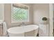 Relaxing bathroom featuring a free-standing tub, decorative window, and bright, neutral tones at 8261 Twin Pointe Cir, Indianapolis, IN 46236