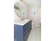 Stylish bathroom featuring blue vanity with quartz countertop, brushed gold hardware, and round mirror at 8429 Catamaran Dr, Indianapolis, IN 46236