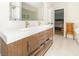 Modern bathroom with double sinks, wood-look cabinets, bright lighting, and views to the bedroom at 8429 Catamaran Dr, Indianapolis, IN 46236