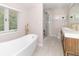 Well-lit bathroom featuring a soaking tub, a shower, and a vanity with double sinks and gold fixtures at 8429 Catamaran Dr, Indianapolis, IN 46236