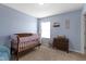 Light blue bedroom with a crib, dresser, stuffed animals and window with white curtains at 8720 N Deer Crossing Blvd, McCordsville, IN 46055