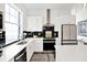 Contemporary kitchen featuring white cabinetry, stainless steel appliances, a black backsplash, and an abundance of natural light at 920 Veterans Way # 204, Carmel, IN 46032