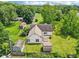 Aerial view displaying a spacious backyard with a wooden deck, multiple storage sheds, and mature trees at 10444 Indian Lake N Blvd, Indianapolis, IN 46236