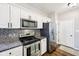 Modern kitchen featuring white cabinets, stainless steel appliances, granite countertops, and a stylish backsplash at 10444 Indian Lake N Blvd, Indianapolis, IN 46236
