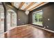 Sitting room featuring hardwood floors, a beamed ceiling, decorative lighting, and a view of the landscaped yard at 10444 Indian Lake N Blvd, Indianapolis, IN 46236