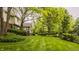 Large backyard with mature trees, lush lawn, and view of the home's exterior at 11875 Durbin Dr, Carmel, IN 46032