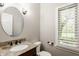 Stylish powder room featuring granite countertop vanity, oval mirror, and plantation shutters for added privacy at 11875 Durbin Dr, Carmel, IN 46032