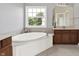 Bathroom featuring a large soaking tub beneath a bright window, and vanity with solid surface counters at 12635 Tuscany Blvd, Carmel, IN 46032