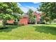 Charming two-story red brick home with a well-manicured lawn and mature trees at 12635 Tuscany Blvd, Carmel, IN 46032