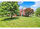 Beautifully landscaped red brick home with a lush green lawn and mature trees at 12635 Tuscany Blvd, Carmel, IN 46032
