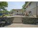 Stone retaining wall and steps up to a patio area with outdoor furniture and a shed at 1524 Northcrest Dr, Anderson, IN 46012