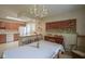 A bright dining room featuring a vintage chandelier, wooden table and chairs, with the kitchen in the background at 1524 Northcrest Dr, Anderson, IN 46012