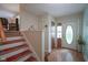 Bright foyer with hardwood floors, decorated stairs and decorative door at 1524 Northcrest Dr, Anderson, IN 46012