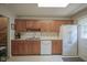View of the kitchen with wood cabinets, a stainless steel sink, and a white refrigerator and dishwasher at 1524 Northcrest Dr, Anderson, IN 46012