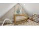 Bright bedroom features sloped ceiling, carpet, and a wooden crib with plenty of natural light at 1623 Hoyt Ave, Indianapolis, IN 46203