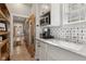 A kitchenette with a stainless steel microwave, white cabinets, a sink and a view of the entryway at 1623 Hoyt Ave, Indianapolis, IN 46203