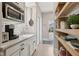 Bright pantry space with stainless steel microwave, white cabinets, open shelving, and view of exterior at 1623 Hoyt Ave, Indianapolis, IN 46203