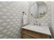 Stylish powder room adorned with patterned wallpaper, vanity, and a round mirror at 1623 Hoyt Ave, Indianapolis, IN 46203