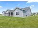 Backyard view featuring a manicured lawn, patio seating, and the home's gray vinyl siding at 19387 Astoria Ave, Sheridan, IN 46069