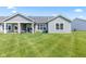 Backyard view featuring a manicured lawn, covered patio seating, and the home's gray vinyl siding at 19387 Astoria Ave, Sheridan, IN 46069