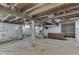 Unfinished basement with concrete floors, utility shelving, water heater, and exposed ceiling beams at 2245 N Ritter Ave, Indianapolis, IN 46218