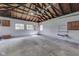 Spacious garage interior with concrete flooring, wooden beams, shelving and multiple windows at 2245 N Ritter Ave, Indianapolis, IN 46218