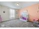 A well-lit bedroom with carpet, peach accent wall, and a white toddler bed at 2426 Autumn Rd, Indianapolis, IN 46229