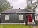 Charming single-story home with dark siding, bright red door, and neatly maintained landscaping at 2954 N Drexel Ave, Indianapolis, IN 46218