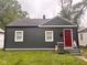 Charming bungalow-style home featuring dark gray siding and a bright red front door at 2954 N Drexel Ave, Indianapolis, IN 46218