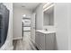 Well-lit bathroom featuring a gray vanity, wood-look flooring, and an open doorway to the kitchen at 3529 Hunt St, Plainfield, IN 46168