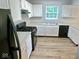 Kitchen featuring white cabinets, black appliances, and wood-look flooring at 6412 Cradle River Dr, Indianapolis, IN 46221