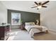 Cozy bedroom featuring a dark green accent wall, ceiling fan, and natural light from a window at 7029 Kingswood Cir, Indianapolis, IN 46256