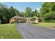 Wide asphalt driveway leading to a brick home, complemented by manicured lawns and mature trees at 7029 Kingswood Cir, Indianapolis, IN 46256