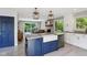 Modern kitchen featuring a blue island with a farmhouse sink and open floor plan to the dining area at 7029 Kingswood Cir, Indianapolis, IN 46256