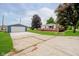 Exterior view of a house with a detached garage, expansive driveway, and lush greenery at 91 N Raceway Rd, Indianapolis, IN 46234