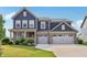 Inviting two-story home boasts a three-car garage, manicured lawn, and classic blue siding at 9671 Ridgecrest Ln, McCordsville, IN 46055