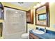 Bright bathroom with shower-tub, vanity with blue countertop, dark wood cabinets and trim, and white tile flooring at 1000 Leisure Ln, Greenwood, IN 46142