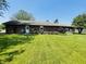 Large grassy backyard featuring a brick home, mature bushes, and a patio at 1008 Whispering Trl, Greenfield, IN 46140